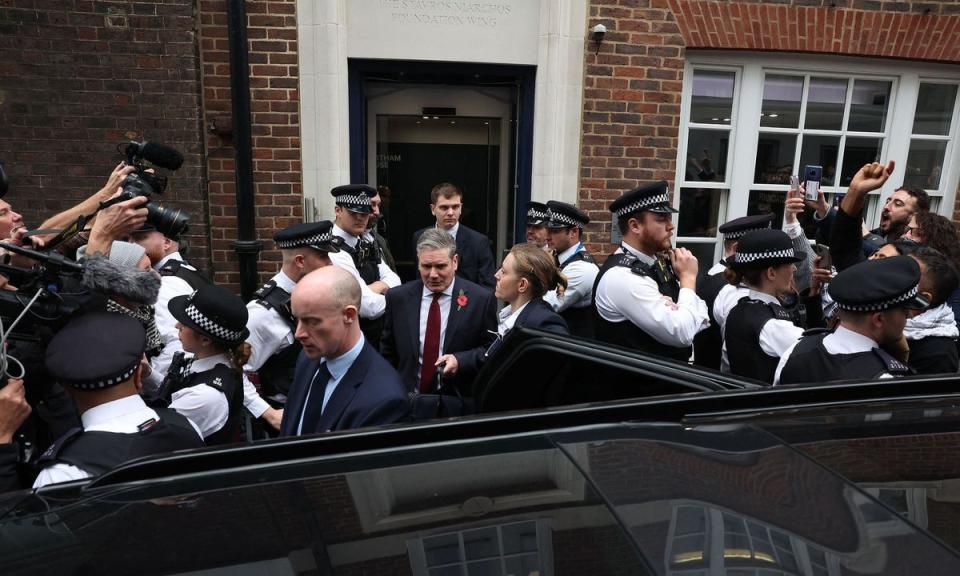 Keir Starmer walks to his waiting car past police officers as demonstrators protest outside of Chatham House in central London (AFP via Getty Images)