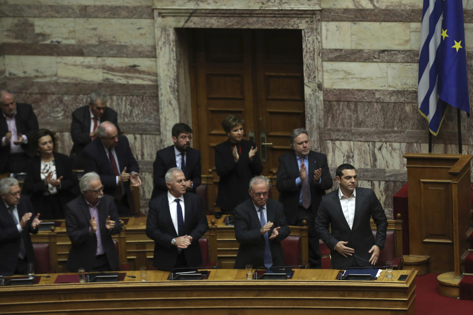 Greek Prime Minister Alexis Tsipras, right, applauded by lawmakers after the end of his speech during a parliamentary session in Athens, on Tuesday, Jan. 15, 2019.Greece's prime minister is defending his deal to normalize relations with neighboring Macedonia ahead of a confidence vote in parliament after his governing coalition collapsed over the agreement. (AP Photo/Petros Giannakouris)