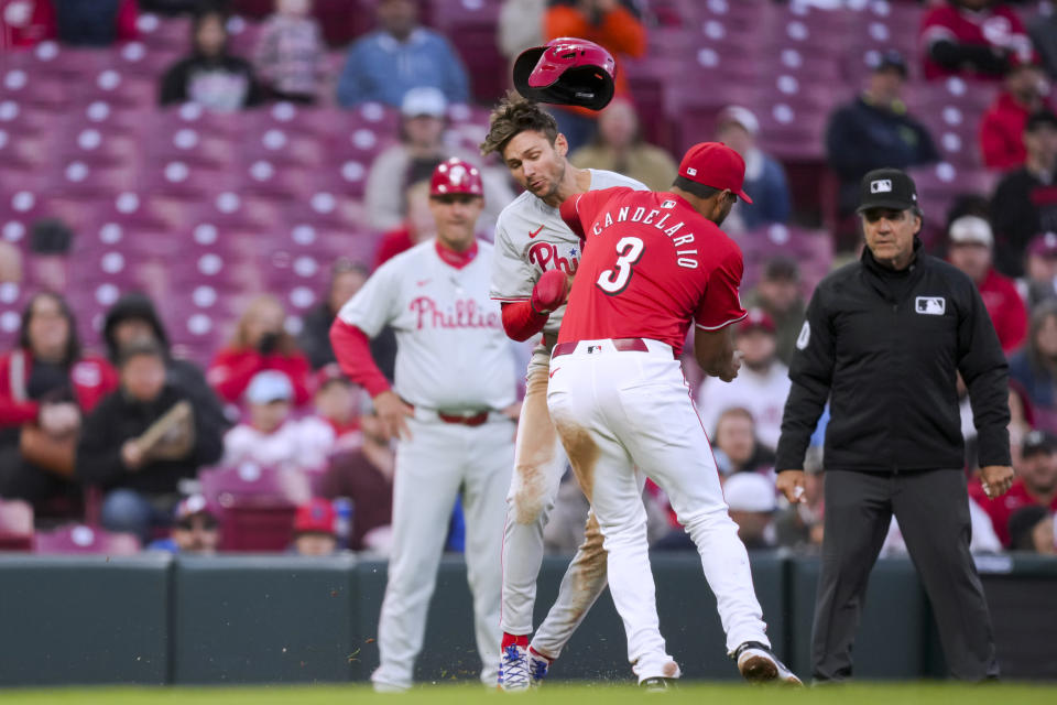 Philadelphia Phillies' Trea Turner, middle, is tagged out by Cincinnati Reds' Jeimer Candelario, right, on a steal attempt during the fifth inning of a baseball game in Cincinnati on Friday, Wednesday, April 24, 2024. (AP Photo/Aaron Doster)