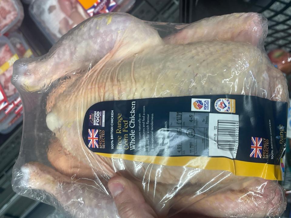 hand holding up a whole chicken at aldi