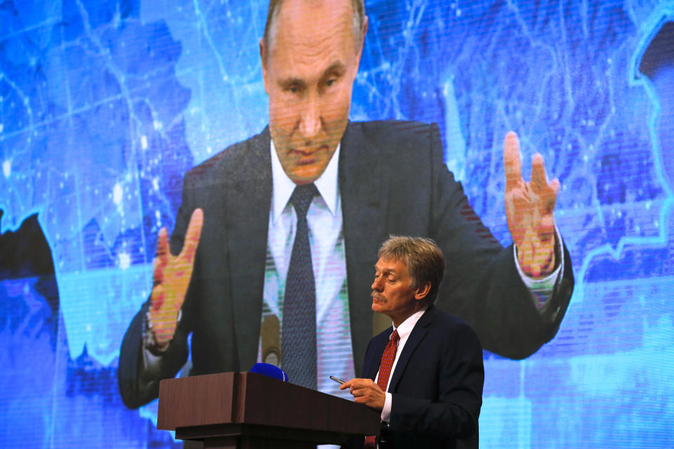 Kremlin spokesman Dmitry Peskov, bottom, looks on as Russian President Vladimir Putin speaks via video call during a news conference in Moscow, Russia, Thursday, Dec. 17, 2020. This year, Putin attended his annual news conference online due to the coronavirus pandemic. (AP Photo/Alexander Zemlianichenko)