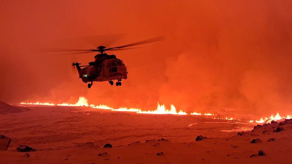 An Icelandic Coast Guard helicopter overflying a volcanic eruption on the Reykjanes peninsula, 3km north of Grindavik, western Iceland on 19 December (HANDOUT/AFP via Getty Images)