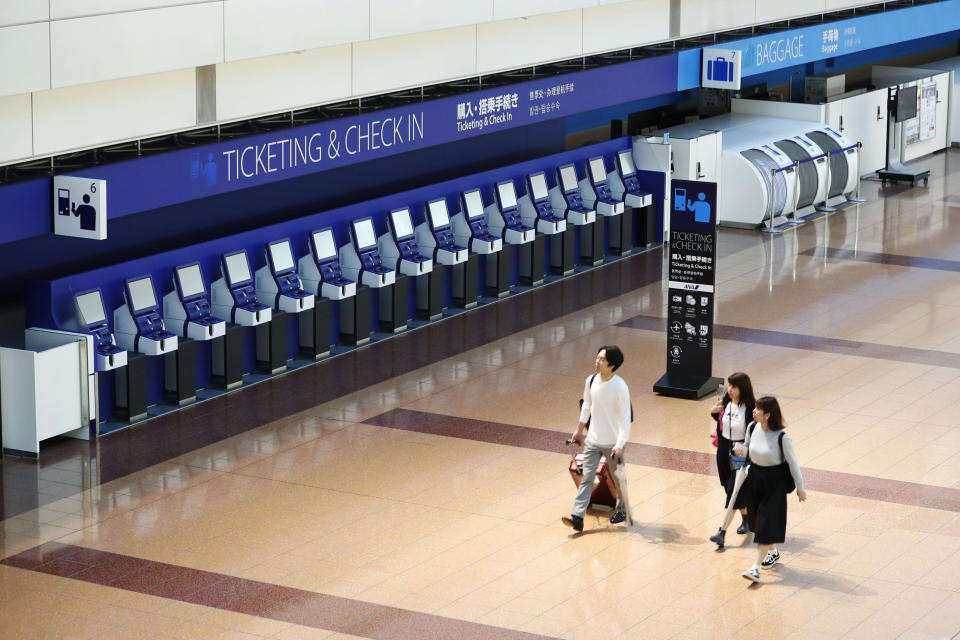 People walk through a quiet terminal at Haneda airpot in Tokyo Saturday, Oct. 12, 2019. Tokyo and surrounding areas braced for a powerful typhoon forecast as the worst in six decades, as it swerved northward over the Pacific toward Japan Saturday. (Masanori Takei/Kyodo News via AP)