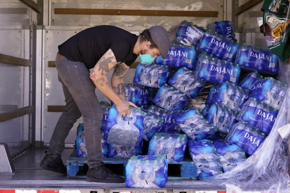 FILE - In this Feb. 23, 2021 file photo, volunteer Ben Harper prepares to hand out drinking water at an apartment complex without water in Dallas. Texas officials on Thursday, March, 25, 2021 raised the death toll from February's winter storm and blackouts to at least 111 people — nearly doubling the state's initial tally following one of the worst power outages in U.S. history. (AP Photo/LM Otero, File)