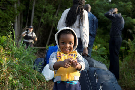 Two-year-old Evanston, whose family stated they are from Haiti, waits to enter into Canada from Roxham Road in Champlain, New York, U.S. August 11, 2017. REUTERS/Christinne Muschi