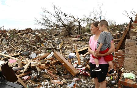 Tracy Stephan, holding her son Timothy, 3, looks at her tornado-destroyed home on 6th Avenue in Moore, Oklahoma in this May 23, 2013 file photo. REUTERS/Rick Wilking/Files