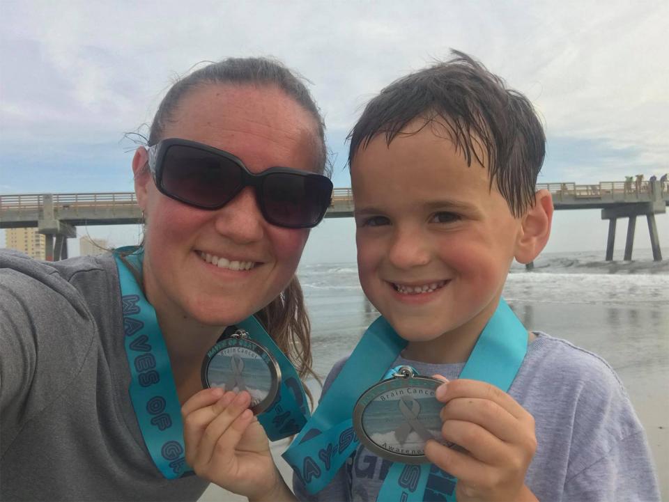 Rebecca Rhodes Kozlosky and son Michael Rhodes show off their medals from the Waves of Gray 5K walk, a Jacksonville Beach fundraiser for brain cancer research. They take part in honor of her first husband and Michael's father, Dustin Rhodes, who died of brain cancer eight years ago.