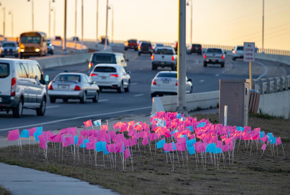 Members of the 14th Judicial Circuit's Human Trafficking Task Force held a vigil at the Hathaway Bridge on Tuesday. The candlelight vigil was in honor of National Human Trafficking Awareness Day. The 282 flags represent the number of child victims in Northwest Florida.