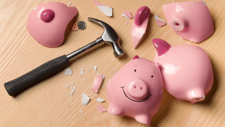  Smashed piggy bank with a hammer lying next to it. 