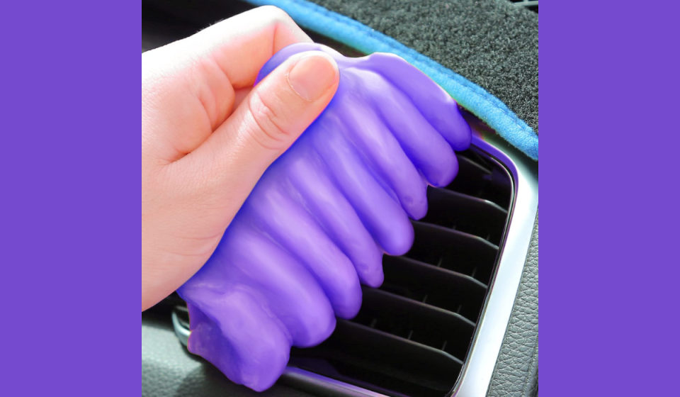 hand using purple cleaning gel on car vents