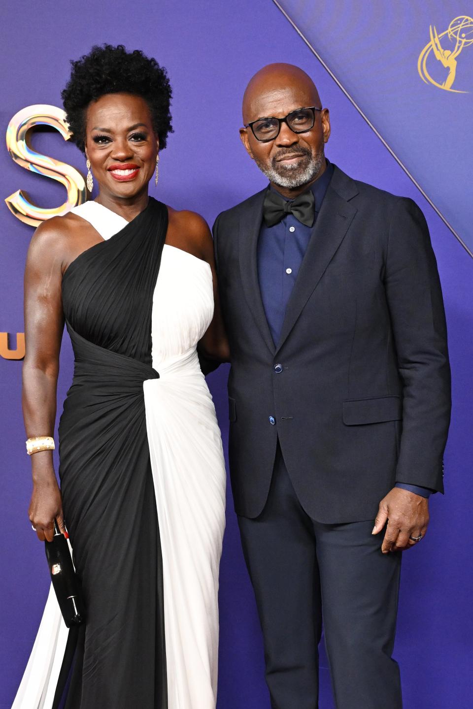 Viola Davis, in a one-shoulder black and white gown, stands with Julius Tennon in a dark suit and bow tie at a celebrity event