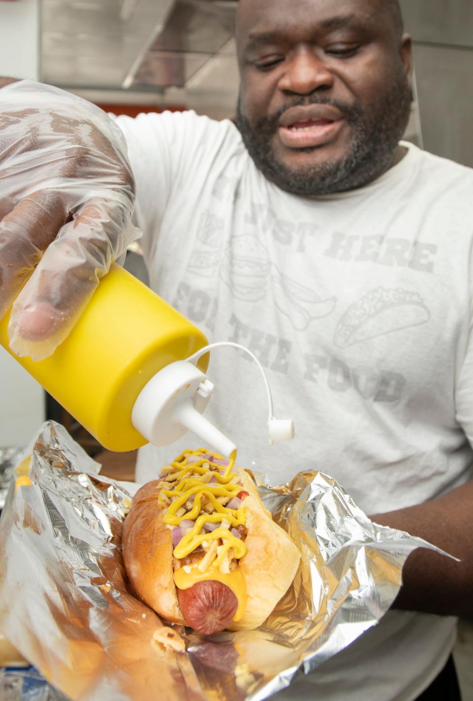 T.P. Whatadogs owner Ronald Pernell tops off a Pernell Whatadog at the North Pace Boulevard restaurant on Monday.