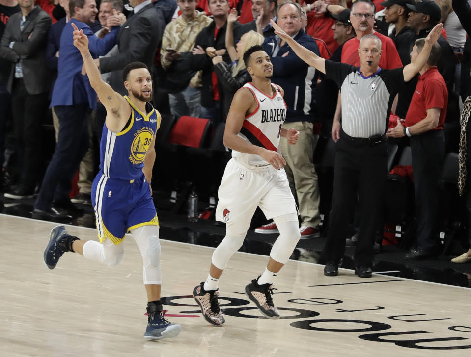 Golden State Warriors guard Stephen Curry, left, celebrates as he runs next to Portland Trail Blazers guard CJ McCollum, center, at the end of Game 4 of the NBA basketball playoffs Western Conference finals, Monday, May 20, 2019, in Portland, Ore. The Warriors won 119-117 in overtime. (AP Photo/Ted S. Warren)
