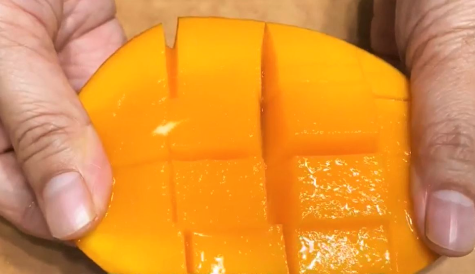 芒果分半，用刀在果肉上畫出方格。