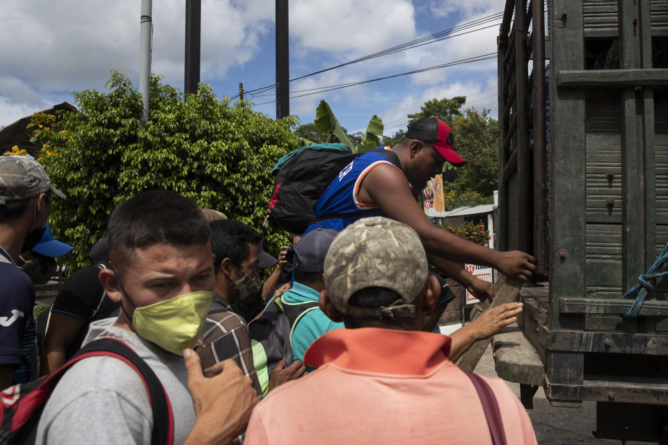 Honduras migrants get on an army truck before returning home, in Morales, Guatemala, Saturday, Oct. 3, 2020. Early Saturday, hundreds of migrants who had entered Guatemala this week without registering were being bused back to their country's border by authorities after running into a large roadblock. (AP Photo/Moises Castillo)