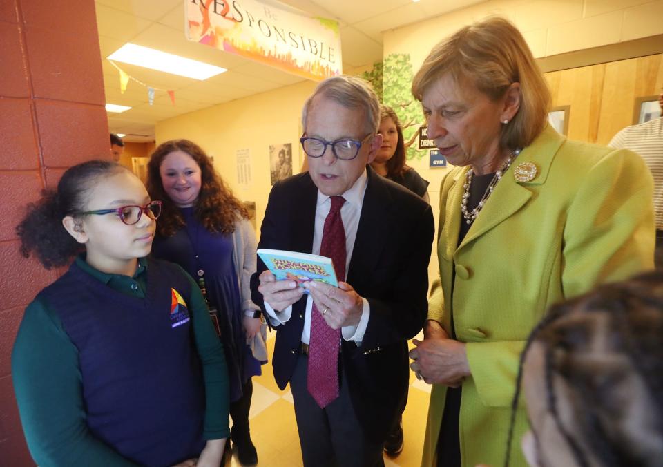 Aliyah Klee shows Gov. Mike DeWine and First Lady Fran DeWine a book, "Billy and the Mini Monsters," she chose from the book vending machine at Helen Arnold Community Learning Center on Tuesday in Akron.