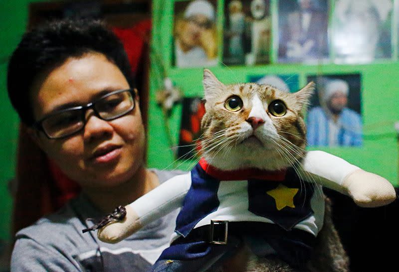 Risma Sandra Irawan, 31, carries her cat wearing a cosplay costume, in Jakarta
