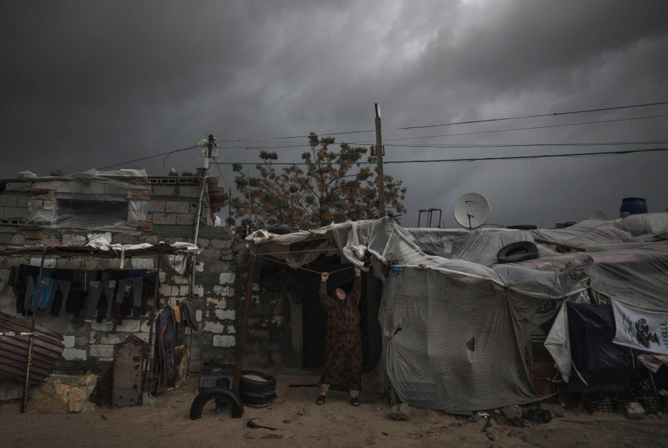 FILE - In this Jan. 20, 2021 file photo, a Palestinian woman checks the nylon cover on the roof of her house on a rainy day in a poor neighborhood of Khan Younis, in the southern Gaza Strip. When the Palestinians last held elections 15 years ago, the Islamic militant group Hamas won a landslide victory after campaigning as a scrappy resistance movement. That will be a harder sell this time around. Top Hamas officials have decamped to luxury hotels in Turkey and Qatar, leaving ordinary Palestinians to suffer the consequences of their policies. (AP Photo/Khalil Hamra, File)