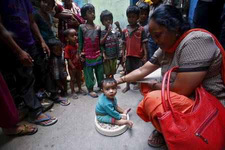 A health worker (R) weighs a child under a government program in New Delhi, India, May 7, 2015. REUTERS/Anindito Mukherjee