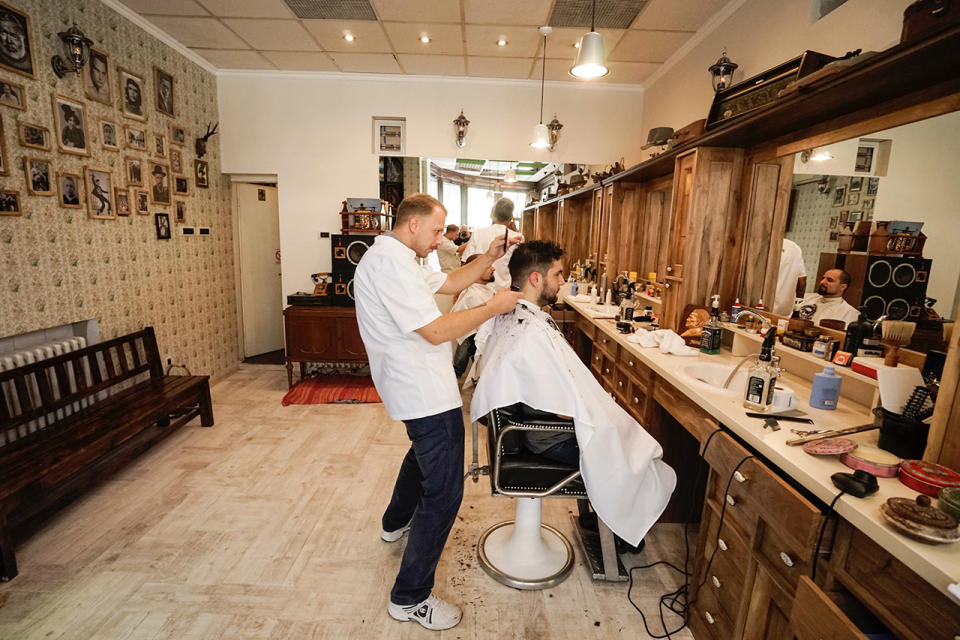 <p>Barber gets low for a haircut at a barbershop in Belgrade, Republic of Serbia. </p>