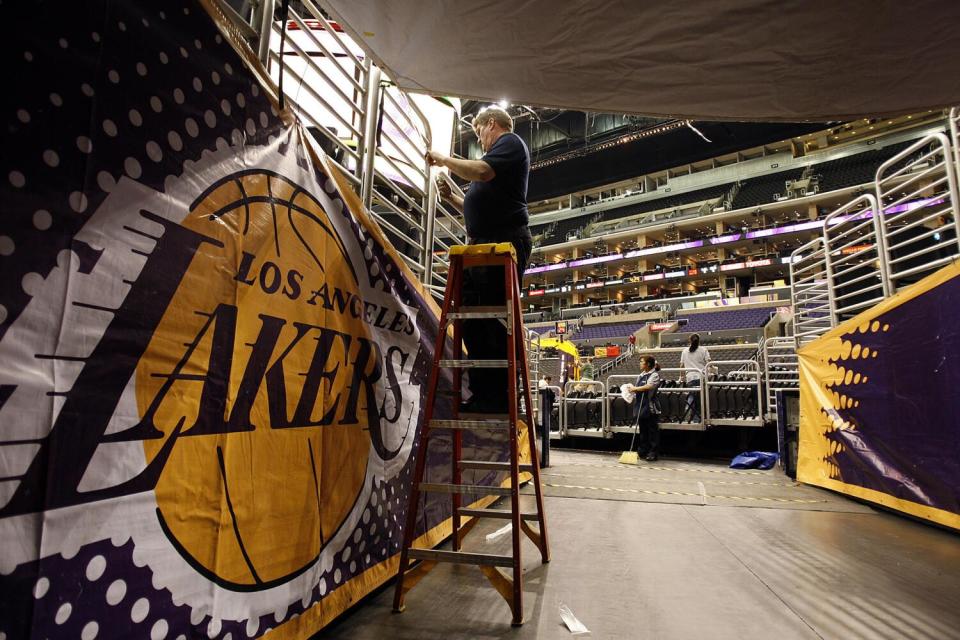 An arena worker puts up a Lakers banner in a tunnel as its converted from a Clippers game played earlier in the day.