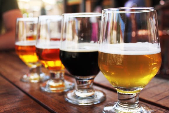 A flight of four different beers sitting on a bar.