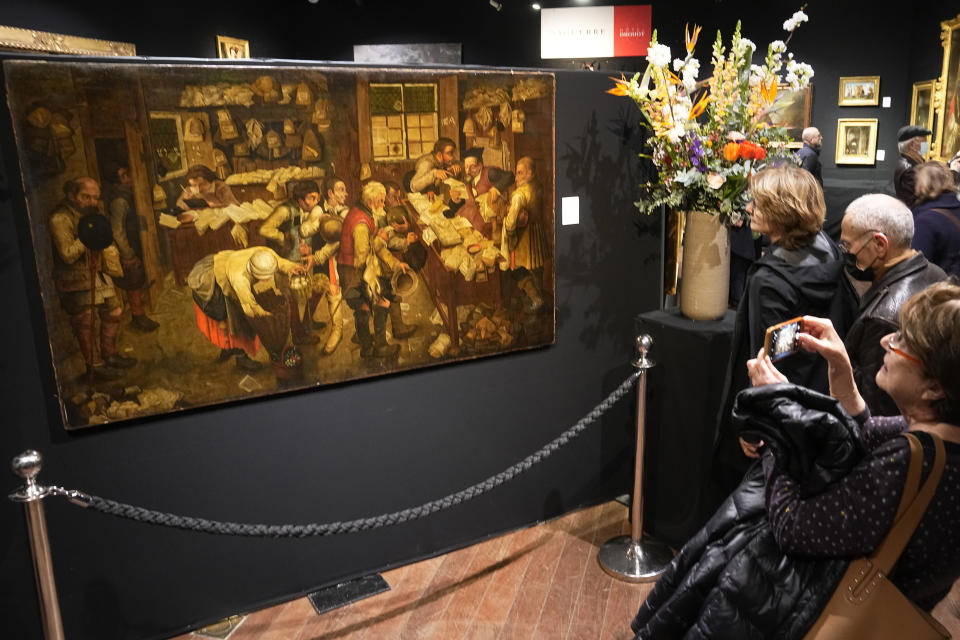 Visitors watch the painting "Payment of the Yearly Dues", also known as "The Peasants' Lawyer" by Pieter Brueghel The Young, estimated to be dating before 1618, at the Drouot auction house in Paris, Monday, March 27, 2023. A rare Brueghel the younger painting found behind a door in French home goes under the hammer in Paris at Drouot Auction house. (AP Photo/Michel Euler)