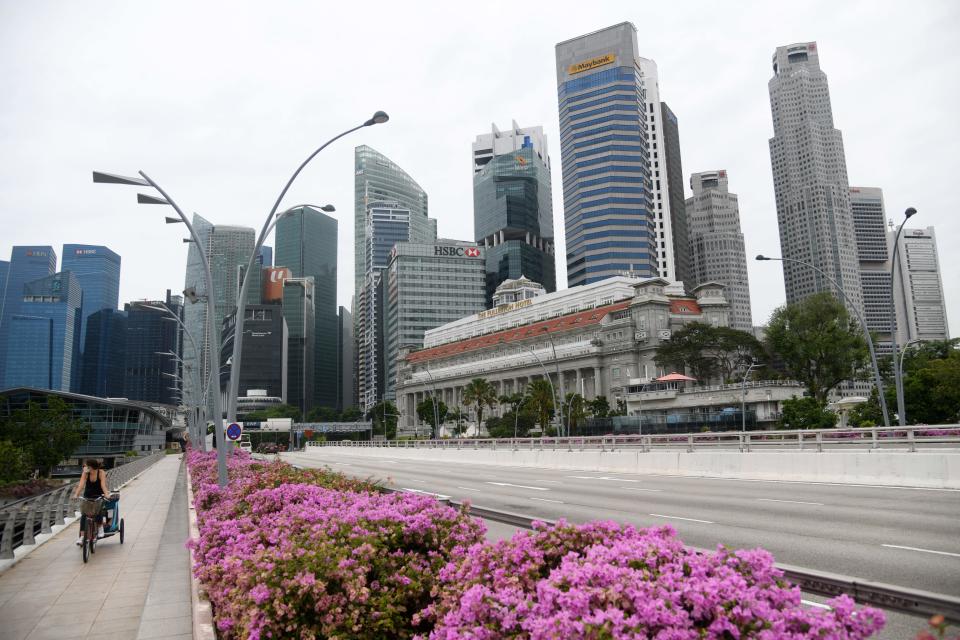A woman cycles past the financial business district in Singapore on May 27, 2020, as restrictions aimed at preventing the spread of the COVID-19 novel coronavirus currently remain in place. (Photo by Roslan RAHMAN / AFP) (Photo by ROSLAN RAHMAN/AFP via Getty Images)