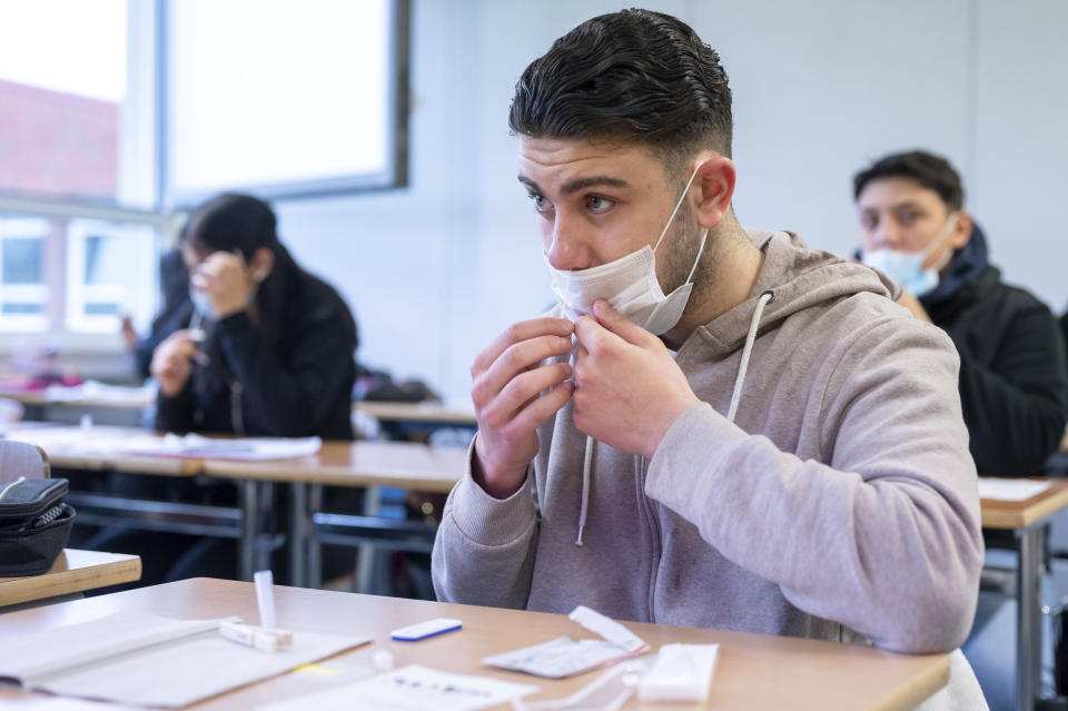 A pupil takes a Corona antigen rapid test before the start of lessons at the Katharina Henoth Comprehensive School in Cologne, Germany, Monday, April 19, 2021. After a week of lessons at home, many children and adolescents in North Rhine-Westphalia have been able to return to their schools for face-to-face lessons since Monday. (Marius Becker/dpa via AP)