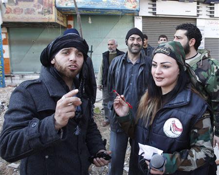 A member of Syria's armed opposition forces (L) speaks with a woman from the National Defense Force, which is loyal to Syria's President Bashar al-Assad, in Babila town, southeast Damascus February 17, 2014, after a local ceasefire agreement was reached between the opposition and regime forces. Picture taken during a guided tour by the Syrian Army. REUTERS/Khaled al-Hariri