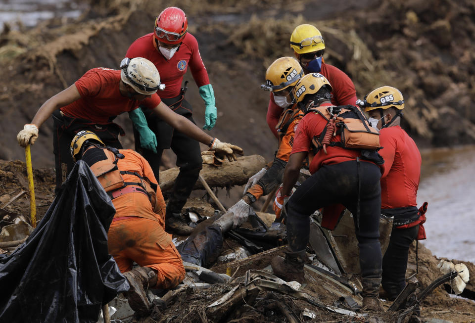 FILE - In this Jan. 28, 2019 file photo, firefighters pull a body from the mud days after a dam collapse in Brumadinho, Brazil. The wave of mud and debris that on Jan. 25, 2019 buried the equivalent of 300 soccer pitches and killed 270 people, continues to barrel over residents’ minds, the local economy and the environment, one year later. (AP Photo/Leo Correa)