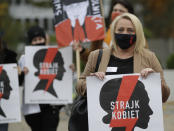 Women's rights activists with posters of the Women's Strike action protest against recent tightening of Poland's restrictive abortion law in front of the parliament building as inside, guards had to be used to shield right-wing ruling party leader Jaroslaw Kaczynski from angry opposition lawmakers, in Warsaw, Poland, on Tuesday, Oct. 27, 2020. Massive nationwide protests have been held ever since a top court ruled Thursday that abortions due to fetal congenital defects are unconstitutional. Slogan reads 'Women’s Strike'. (AP Photo/Czarek Sokolowski)