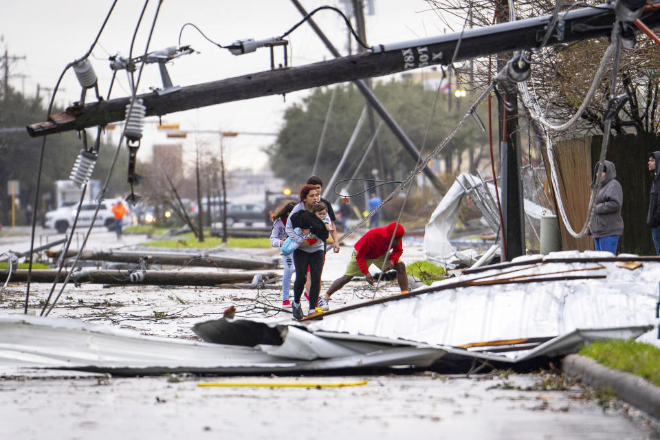 People cross under downed power lines after a tornado passed through Pasadena, Texas  (Mark Mulligan / Houston Chronicle via AP)