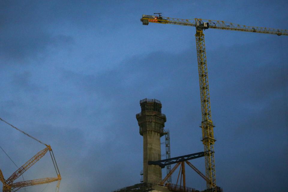 A fire flickers at the top of a crane being used to work on the new Harbor Bridge project on Saturday, April 22, 2023, in Corpus Christi, Texas. Two people at Whataburger Field were injured by "shrapnel" from the fire during a Corpus Christi Hooks game, Assistant Fire Chief Doug Matthijetz said.