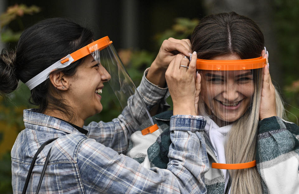 Students try out a new face shield to fight the coronavirus pandemic at a school in Cologne, Germany, Monday, May 25, 2020. The local manufacturer of plastic plain bearings IGUS produces and donates about 140,000 face shields for all students in the city. The effective protection of the easy to assemble shield was tested before at the school in Cologne by pupils, when face masks became mandatory. (AP Photo/Martin Meissner)