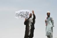 Un homme agite un drapeau taliban au poste-frontière afghan, de l'autre côté du poste pakistanais de Chaman, à la frontière entre Afghanistan et Pakistan, le 17 juillet 2021