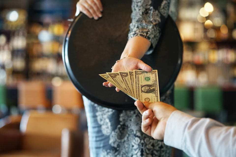 The hand of the waitress takes the tip. The waiter girl receives a tip from the client at the hotel bar. A bartender woman is happy to receive a tip at work. The concept of service.