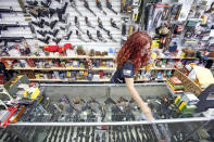 Diane Rowe, owner of Papas Pawn & Gun, disinfects the counter after a costumer came to look at a gun in Grants, N.M., Monday, April 27, 2020. After a year of pandemic lockdowns, mass shootings are back, but the guns never went away. As the U.S. inches toward a post-pandemic future, guns are arguably more present in the American psyche and more deeply embedded in American discourse than ever before. The past year's anxiety and loss fueled a rise in gun ownership across political and socio-economic lines. (Luis Sánchez Saturno/Santa Fe New Mexican via AP, File)