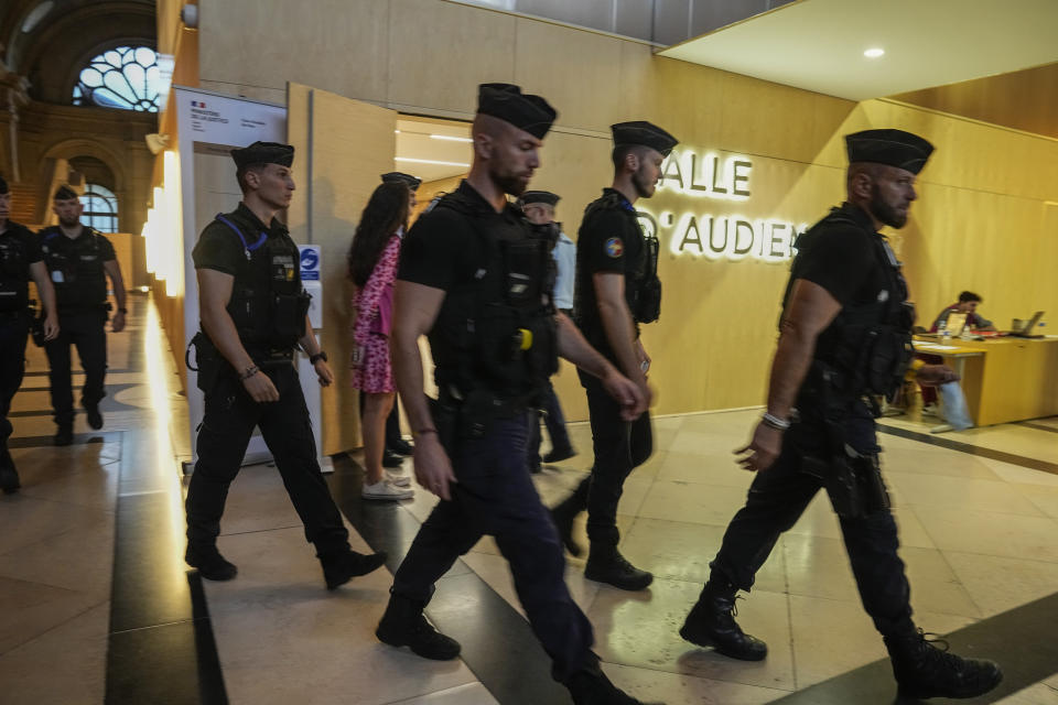 Police officers walk past the the special court room in Paris Wednesday, June 29, 2022. The lone survivor of a team of Islamic State extremists was convicted Wednesday of murder and other charges and sentenced to life in prison without parole in the 2015 bombings and shootings across Paris that killed 130 people in the deadliest peacetime attacks in French history. (AP Photo/Michel Euler)