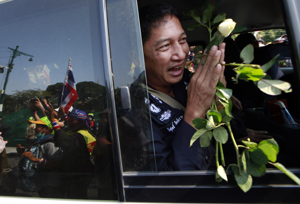 A Thai border policeman holds roses and greets back to anti-government protesters while leaving the prime minister's office of government house Sunday, Jan. 19, 2014 in Bangkok, Thailand. Police on Sunday withdrew a number of their unit out of the government house compound under the request of protesters. Two explosions shook an anti-government demonstration site in Thailand's capital on Sunday, wounding at least 28 people in the latest violence to hit Bangkok as the nation's increasingly volatile political crisis drags on. (AP Photo/Wason Wanichakorn)