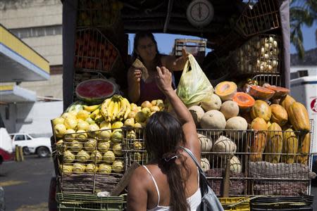 Fernanda Bolivar, 54, buys vegetables from a street vendor close to the Mother Teresa of Calcutta eating center in Caracas March 20, 2014. REUTERS/Carlos Garcia Rawlins