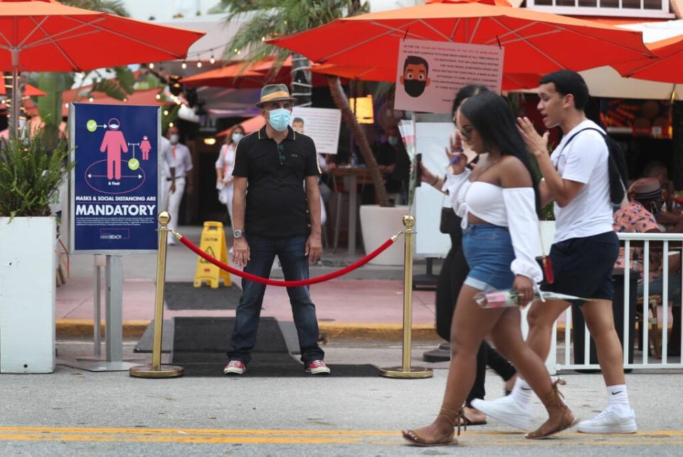 Juan Carlos, a host at Ocean 10 restaurant, stands at the entrance of the restaurant to turn customers away as a curfew from 8pm to 6am is put in place on July 18, 2020 in Miami Beach, Florida. (Photo by Joe Raedle/Getty Images)