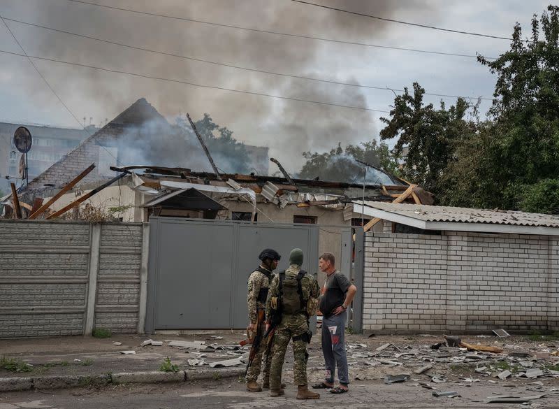 Militares hablan con un residente local mientras su casa arde tras un bombardeo en la región de Luhansk