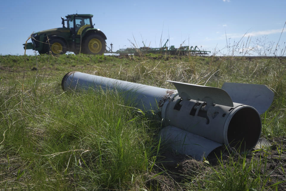 A fragment of a Russian missile is seen in the foreground as a farmer works on his field in Izium, Kharkiv region, Ukraine, Saturday, April 20, 2024. (AP Photo/Andrii Marienko)