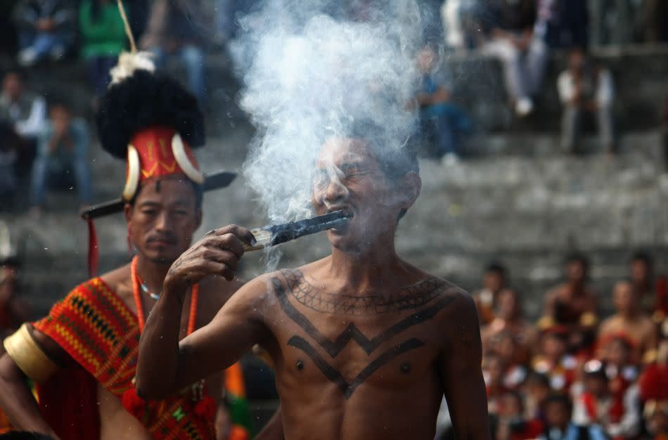 A Naga tribesman from the Konyak tribe eats a stump of smoldering firewood during the second day of the state's annual Hornbill Festival. The Konyak, who hail from the village of Hongphoi from Nagaland's Mon district, are famous for their fire-eating demonstrations.