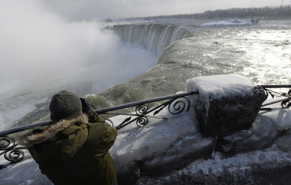 A visitor takes pictures overlooking the falls in Niagara Falls, Ontario, January 8, 2014. The frigid air and "polar vortex" that affected about 240 million people in the United States and southern Canada will depart during the second half of this week, and a far-reaching January thaw will begin, according to AccuWeather.com. REUTERS/Aaron Harris (CANADA - Tags: ENVIRONMENT TRAVEL)