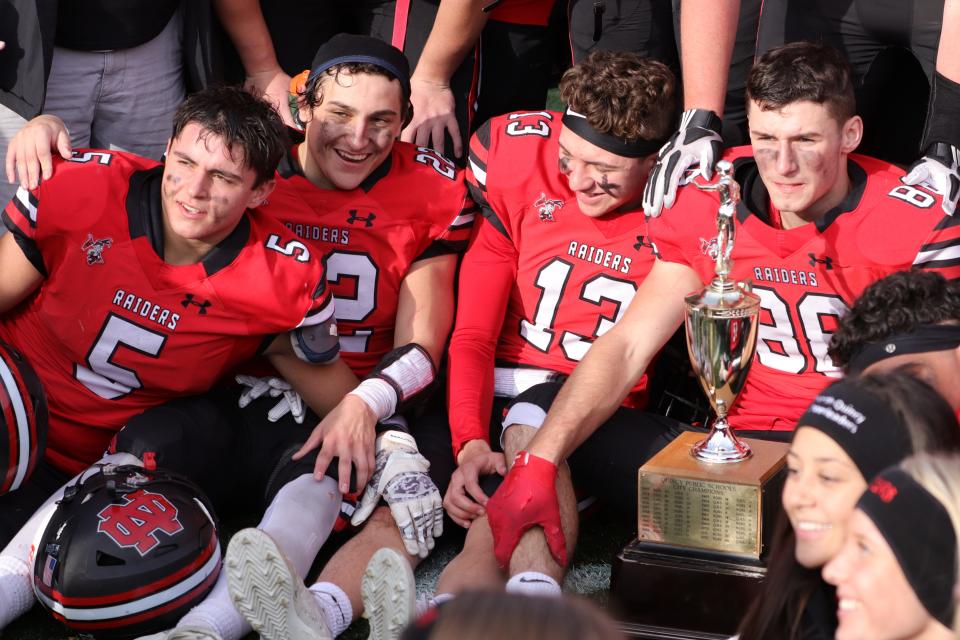 The North Quincy High football team celebrates with the trophy after the 89th  Thanksgiving game against Quincy at Veteran's Memorial Stadium in Quincy on Thursday, Nov. 25, 2021.