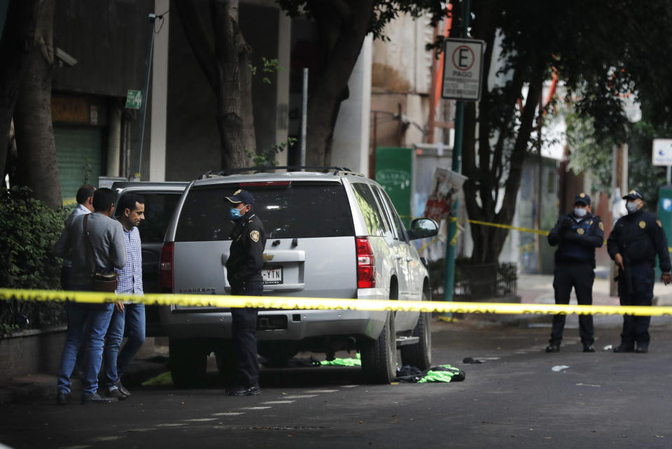 An abandoned vehicle that is believed to have been used by gunmen in an attack against the chief of police is sealed off with yellow tape and guarded by police, in Mexico City, Friday, June 26, 2020. Heavily armed gunmen attacked and wounded Omar Garcia Harfuch in a brazen operation that left an unspecified number of dead, Mayor Claudia Sheinbaum said Friday. (AP Photo/Marco Ugarte)