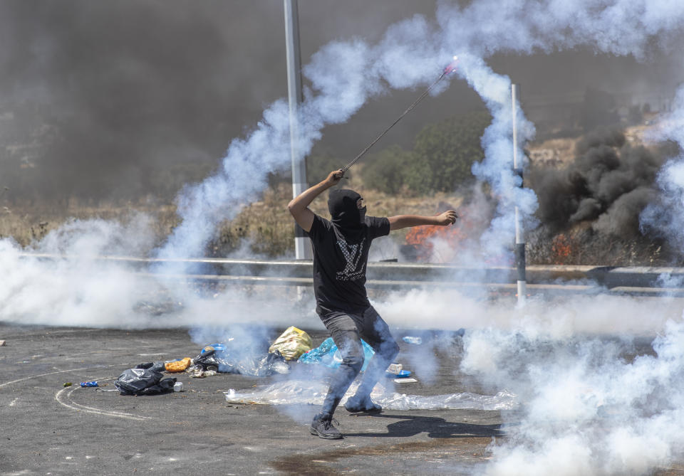 FILE - In this May 18, 2021, file photo, a Palestinian demonstrator uses a slingshot to return a teargas canister toward soldiers during clashes with Israeli troops at the northern entrance of the West Bank city of Ramallah. Israel is at war with Hamas, Jewish-Arab mob violence has erupted inside Israel, and the West Bank is experiencing its deadliest unrest in years. Yet this may all bolster Prime Minister Benjamin Netanyahu. (AP Photo/Nasser Nasser, File)