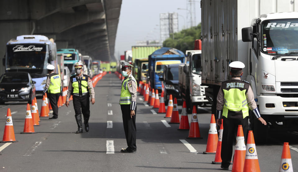 Indonesian police guard at a checkpoint during the imposition of large-scale restriction to curb the spread of the new coronavirus outbreak on a toll road in Cikarang, West Java, Indonesia, Friday, April 24, 2020. Indonesia is suspending passenger flights and rail service as it restricts people in the world's most populous Muslim nation from traveling to their hometowns during the Islamic holy month of Ramadan because of the coronavirus outbreak. (AP Photo/Achmad Ibrahim)